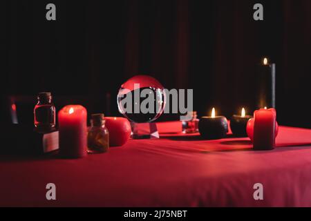 Magic orb vicino candele brucianti su tavola isolato su nero Foto Stock