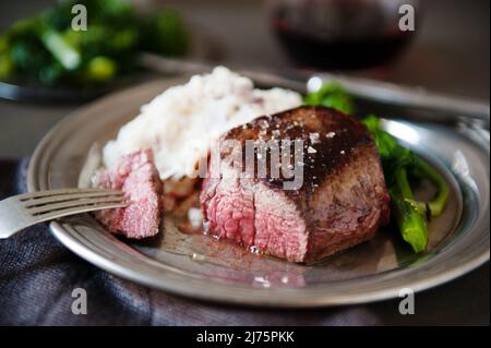 Filetto di Mignon con un pezzo trafitto su una forchetta; servito con purè di patate e coniglio di broccoli Foto Stock