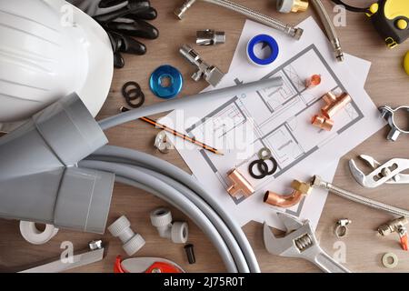 Materiale e strumenti per l'installazione di acqua in una casa con un piano su un banco di lavoro in legno. Vista dall'alto. Composizione orizzontale. Foto Stock