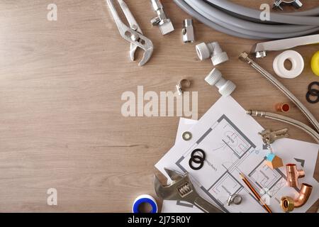 Piani e alloggiamento acqua materiale di installazione su tavola di legno. Vista dall'alto. Composizione orizzontale. Foto Stock