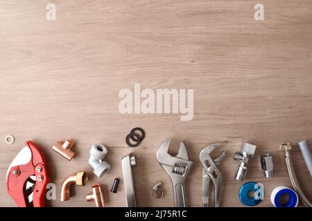 Fila di materiali idraulici e utensili su banco da lavoro in legno vista dall'alto sfondo. Vista dall'alto. Composizione orizzontale. Foto Stock
