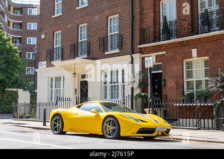 Londra - Maggio 2022: Una Ferrari gialla parcheggiata fuori da attraenti case cittadine a Knightsbridge, una zona ricca di Londra. Foto Stock