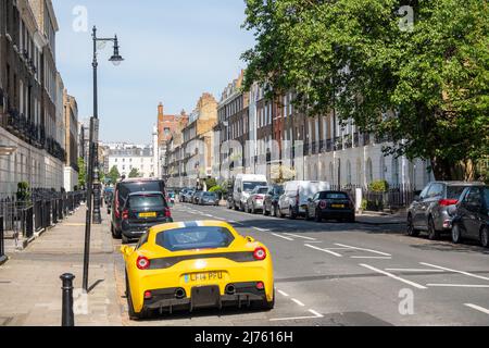 Londra - Maggio 2022: Una Ferrari gialla parcheggiata fuori da attraenti case cittadine a Knightsbridge, una zona ricca di Londra. Foto Stock