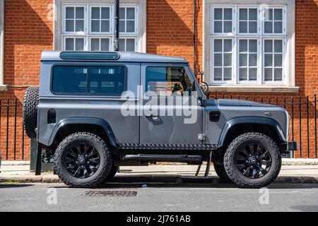 Londra - Maggio 2022: Un veicolo Land Rover Defender a ruote corte parcheggiato di fronte alle attraenti case di Chelsea Foto Stock