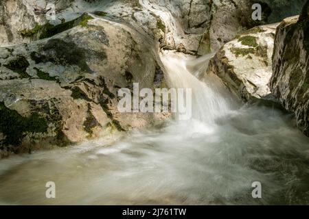 Piccolo ruscello a Kesselberg vicino a Kochel tra rocce nella luce con muschio su pietra. Foto Stock