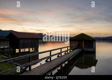 Capanne per barche a Kochelsee, ai piedi delle Alpi bavaresi, nella luce della sera Foto Stock