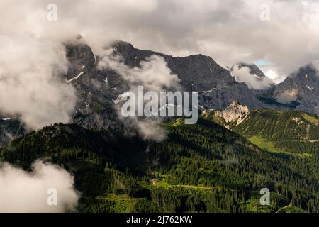 La Rappenklammspitze nella Valle del Rodano nel Karwendel vicino Hinterriss nelle Alpi tirolesi brilla nella luce del pomeriggio, mentre dense nubi basse si raccolgono e le alte pareti della catena del Karwendel settentrionale si innalzano sullo sfondo. Foto Stock