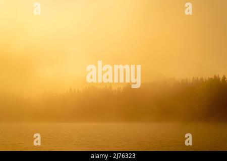 Il Geroldsee, anche Wagenbrüchsee in una mattinata di inizio autunno. La luce dell'alba colora tutto l'arancio dorato, sullo sfondo si vede l'ombra del Karwendel. Foto Stock