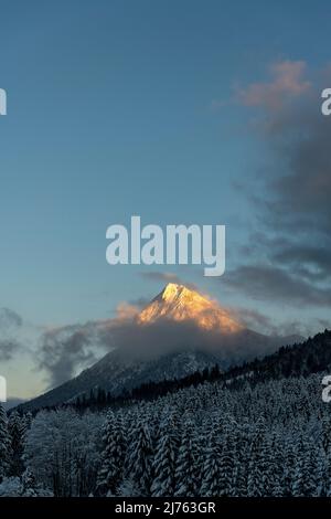 Il Guffert nei monti Rofan, mentre neve in inverno nella luce ultima sera. Alpenglow illumina solo la cima e alcune nuvole. Foto Stock