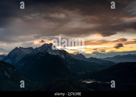 Vista dalla capanna Mittenwald dei monti Wetterstein e dal lago Lautersee vicino a Mittenwald, ai piedi delle Alpi bavaresi, nella sera rossa con le spettacolari nuvole. Foto Stock