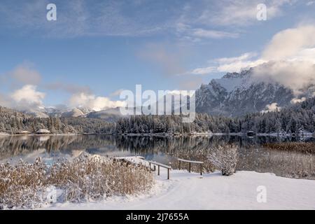 Il Lautersee sopra Mittenwald nella neve fresca di una bella giornata invernale con passerella, sullo sfondo il Karwendel occidentale Foto Stock