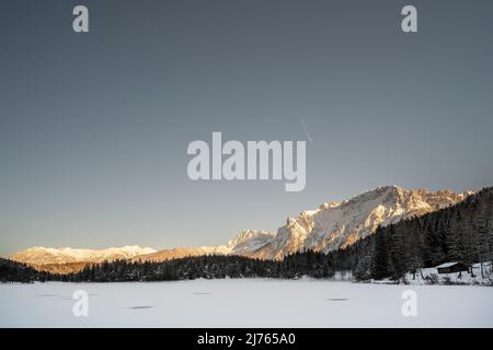 Il Lautersee ghiacciato in neve e ghiaccio in inverno, sullo sfondo il Karwendel nord sopra Mittenwald nella luce del pomeriggio Foto Stock