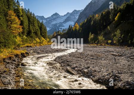 Autunno a Johannisbach a Johannistal vicino Hinterriss a Karwendel, Tirolo / Austria. Il torrente si snoda attraverso il suo letto di ghiaia naturale, sullo sfondo le pareti del Laliderer con la prima neve. Foto Stock