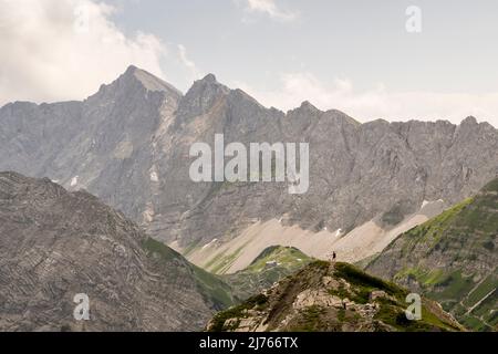 Escursionista in piedi su una collina con vista a Lamsenjochhütte in Karwendel su una cresta in Karwendel. Foto Stock