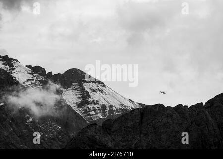 Elicottero che vola attraverso il Karwendel, nelle nuvole di sfondo e la vetta di Kaltwasserkar Foto Stock