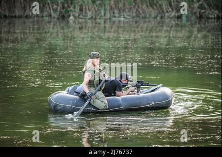 Le forze speciali femminili addestrano nello sbarco barca di gomma che si muove attraverso il fiume. Tiro con le armi da fuoco e allenamento tattico. Foto Stock