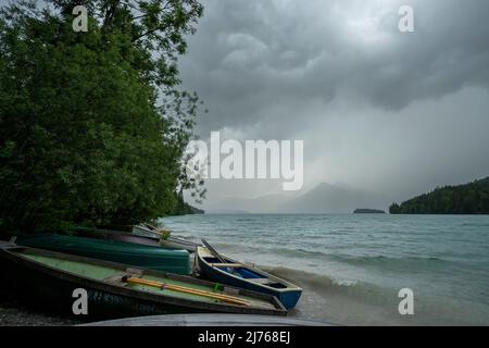 Tempesta all'ormeggio in barca a Niedernach sul lago Walchen. Sulla spiaggia si trovano diverse barche da pesca, sullo sfondo la piccola isola di Sassau e tra le nuvole il Herzogstand. Foto Stock