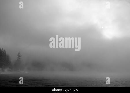 Atmosfera di nebbia cupa con sole che brilla sulla riva di Walchensee in inverno Foto Stock