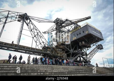 06 maggio 2022, Sassonia-Anhalt, Gräfenhainichen: I visitatori si trovano sotto l'ex escavatore a cielo aperto. Lo stagno delle sarie di Medusa è stato reso accessibile a tutti con e senza handicap. Un ascensore in vetro conduce ad una grande piattaforma panoramica. La misura è stata sostenuta dal programma leader, dal Fondo per il patrimonio mondiale e dagli orientamenti del FESR dell'UE. Foto: Heiko Rebsch/dpa Foto Stock