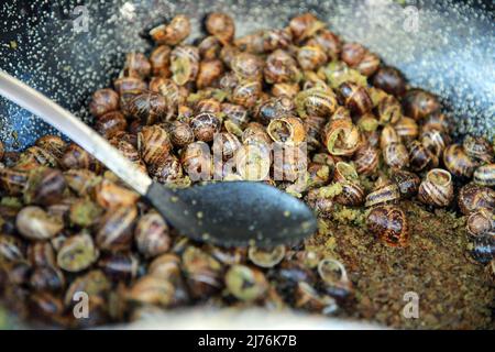 Le lumache vengono cotte in burro all'aglio in un mercato francese. Foto Stock