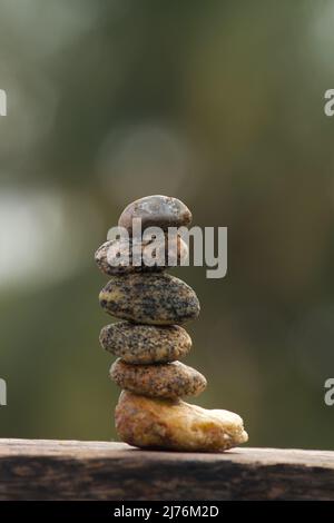 Diversi tipi di sassi in pietra si equilibra su una tavola di legno Foto Stock