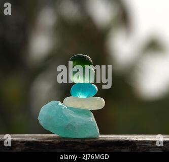 Una vista a primo piano di ciottoli di vetro marino di diversi colori si bilancia su una pietra apatite ruvida Foto Stock