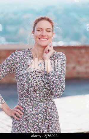 Felice giovane donna rossa che ascolta musica con auricolari vivavoce Foto Stock