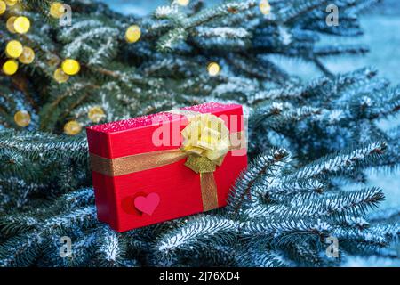 Confezione regalo rossa per San Valentino con cuori su rami di abete. Foto Stock