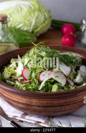 Insalata con cavolo cinese, cetrioli, ravanelli e erba cipollina, condita con olio d'oliva, formato verticale Foto Stock