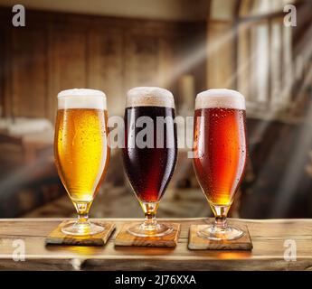 Bicchiere di birra raffreddato con condensa sul tavolo in legno. Pub sfocato sullo sfondo. Foto Stock