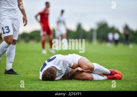 Il calciatore ferito giace sul campo. Foto Stock