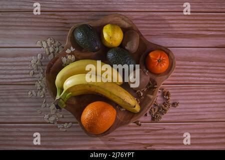 Frutta in un piatto di legno su un tavolo Foto Stock