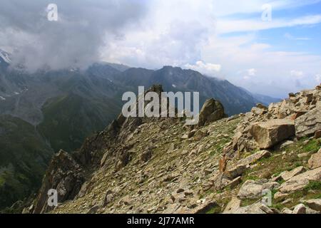 Cresta alpina e rocce in primo piano nella gola Prokhodnoye con cielo e nuvole Foto Stock