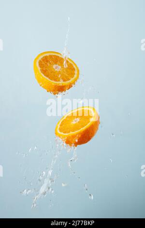 fette di arance in acqua spruzzi su uno sfondo grigio, volando f Foto Stock