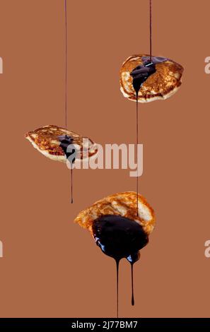 gocce di cioccolato condendo gocciolando dai pancake interi di grano Foto Stock