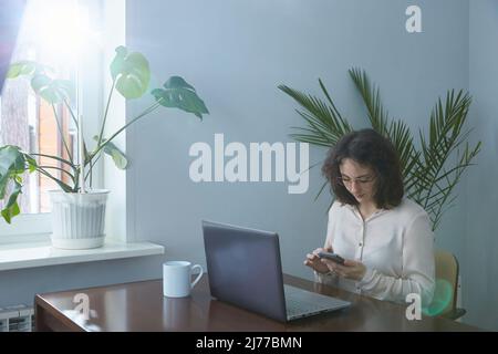 Uno smartphone laptop donna di mezza età Foto Stock