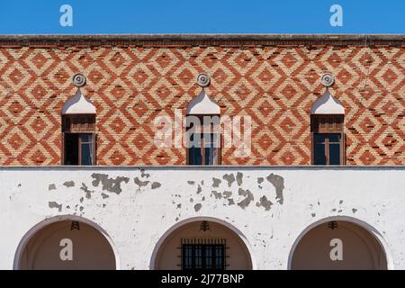 Finestre ad arco in legno antico con balkoni allungati su una vecchia parete bianca. Foto Stock