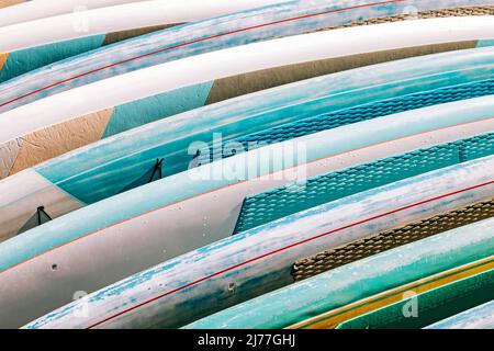 Primo piano di tavole colorate a paddle a noleggio. Attrezzature da spiaggia estive Foto Stock