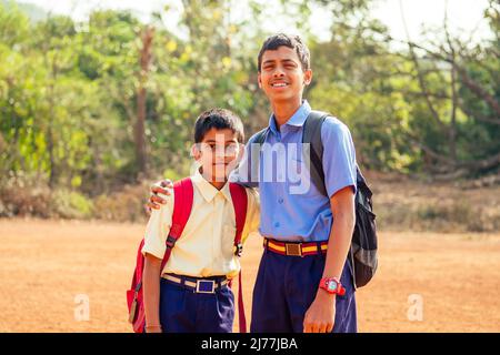 Due fratelli indiani vanno a scuola a Goa all'aperto Foto Stock