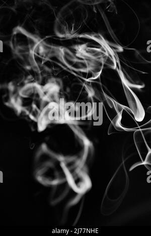 Un modello di fumo bianco, vorticoso, ascendente su uno sfondo nero, la foto potrebbe essere usata come sfondo, trama di fumo o astratto, o pho di stock generale Foto Stock