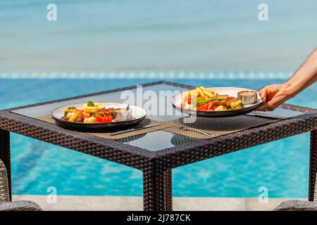 Cameriere maschile che serve il pranzo nel ristorante dell'hotel, concetto di vacanze estive Foto Stock