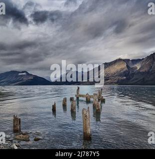 Lago di montagna con resti di vecchio molo di legno al mattino nuvoloso vento Foto Stock