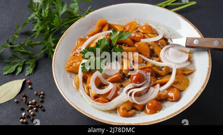 Funghi marinati a base di miele selvatico Armillaria mellea funghi con spezie e cipolle nel recipiente. Foto Stock