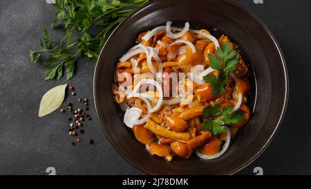 Funghi marinati a base di miele selvatico Armillaria mellea funghi con spezie e cipolle nel recipiente. Foto Stock