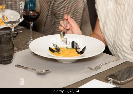 donna che mangia zuppa di panna con pesce in un ristorante Foto Stock