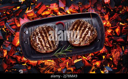 Due bistecche di manzo alla griglia con filetto di mignon sulla padella per barbecue su pezzi caldi di cocco. Vista dall'alto. Foto Stock