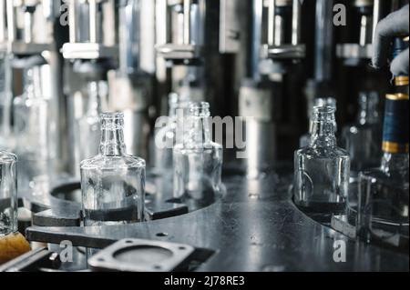 Riempimento di bottiglie di vetro con liquido. Foto Stock