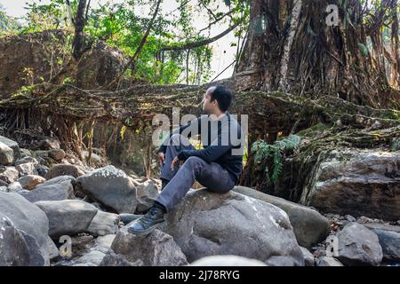 l'uomo giovane con ponte di radice di albero isolato naturale formato singolo piano al giorno da immagine angolo piatto è preso a ponte di radice di ponte singolo meghalaya ind Foto Stock