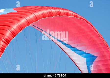 Parapendio rosso in primo piano contro il cielo blu Foto Stock