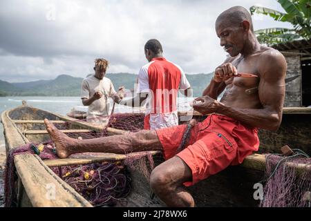 Pescatori che riparano le reti da pesca sulla canoa prima di andare a pescare. Foto Stock